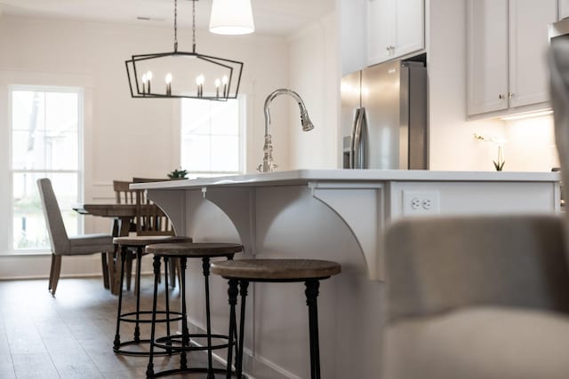 kitchen featuring pendant lighting, an inviting chandelier, stainless steel refrigerator with ice dispenser, dark hardwood / wood-style floors, and white cabinetry