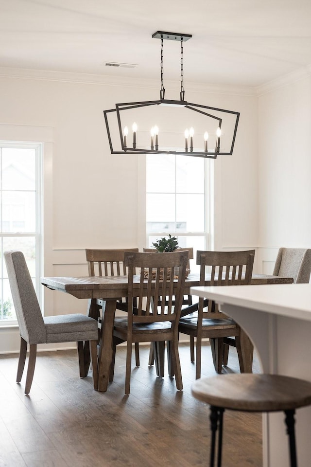 dining room with hardwood / wood-style flooring, a notable chandelier, and ornamental molding