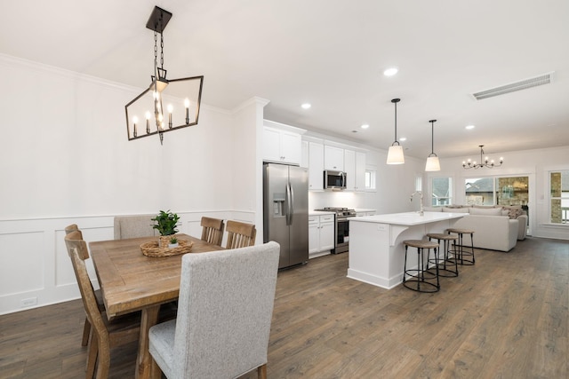 dining room with crown molding, a chandelier, sink, and dark wood-type flooring