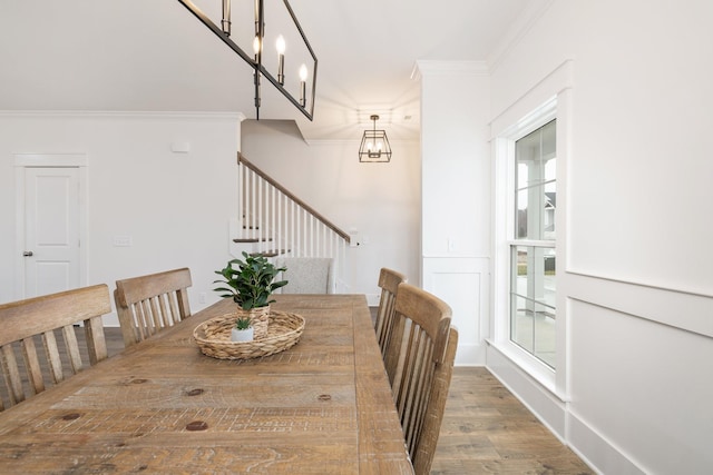 dining room featuring crown molding, wood-type flooring, a healthy amount of sunlight, and an inviting chandelier