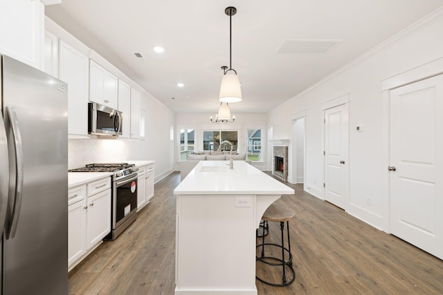 kitchen with pendant lighting, white cabinets, sink, an island with sink, and appliances with stainless steel finishes