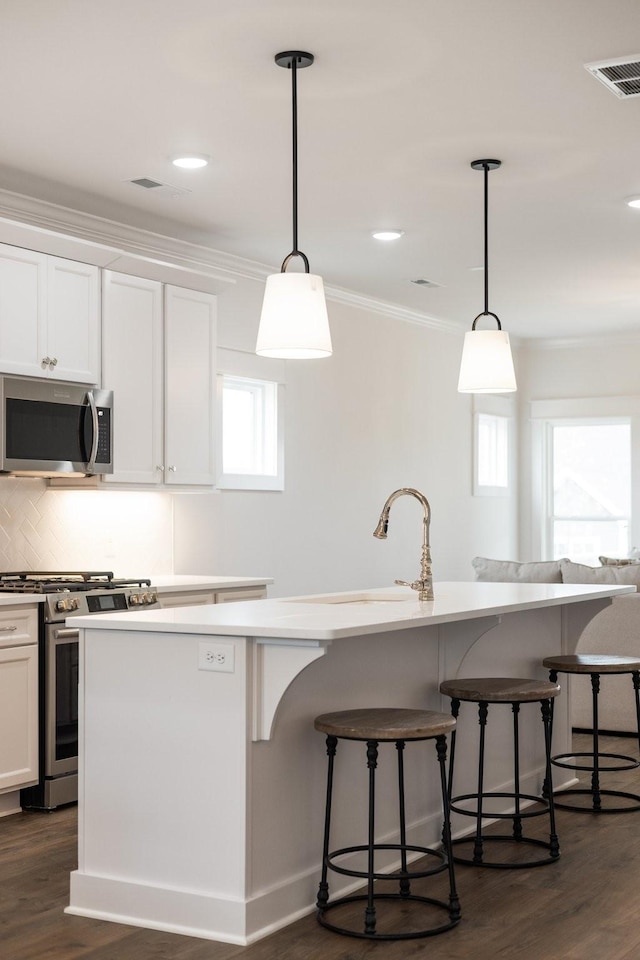 kitchen with dark hardwood / wood-style floors, white cabinetry, hanging light fixtures, and appliances with stainless steel finishes