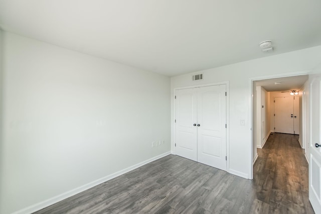 unfurnished bedroom with dark hardwood / wood-style floors and a closet