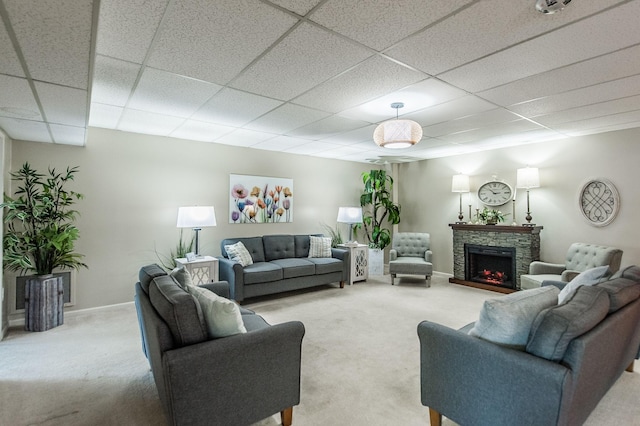 carpeted living room featuring a paneled ceiling and a stone fireplace