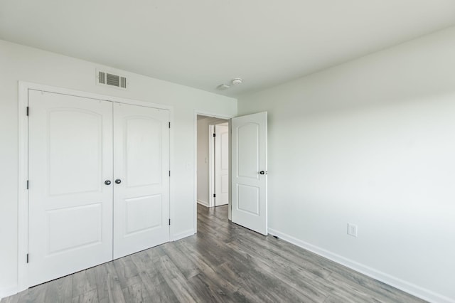 unfurnished bedroom featuring dark hardwood / wood-style flooring and a closet