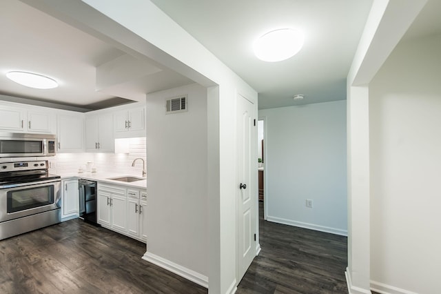 kitchen featuring tasteful backsplash, stainless steel appliances, dark wood-type flooring, sink, and white cabinets