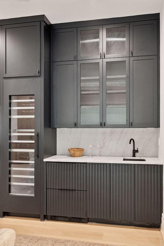 kitchen featuring tasteful backsplash, sink, beverage cooler, and light wood-type flooring