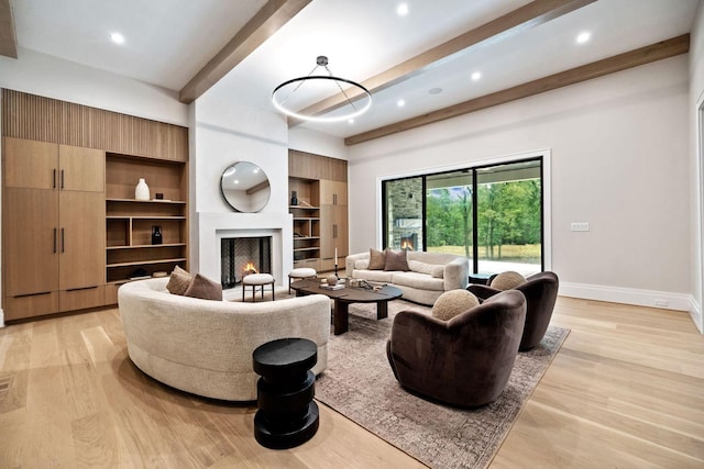 living room featuring a large fireplace, built in features, beamed ceiling, and light hardwood / wood-style floors