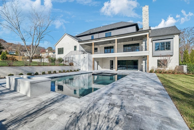 back of house featuring a pool with hot tub, a balcony, and a patio