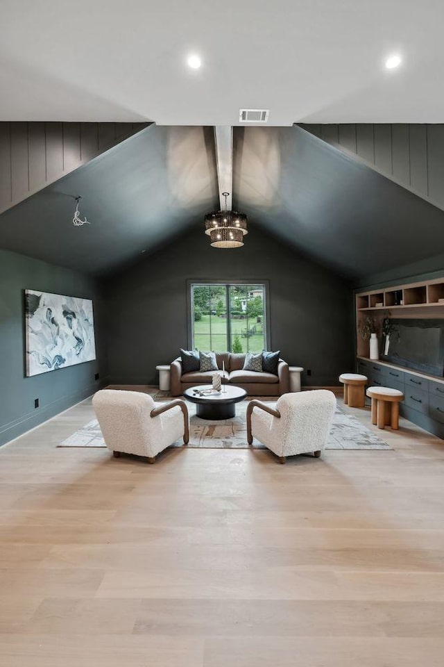 living room featuring an inviting chandelier, light wood-type flooring, and vaulted ceiling