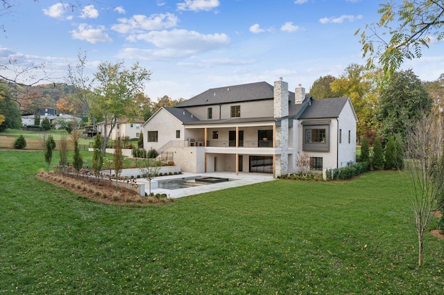 rear view of house featuring a balcony, a yard, and a patio