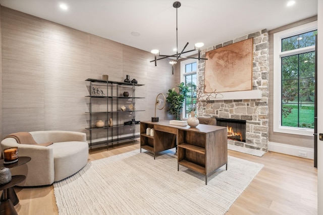 office with an inviting chandelier, a fireplace, and light hardwood / wood-style flooring