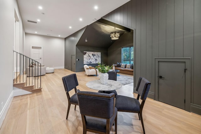 dining area with light wood-type flooring and an inviting chandelier