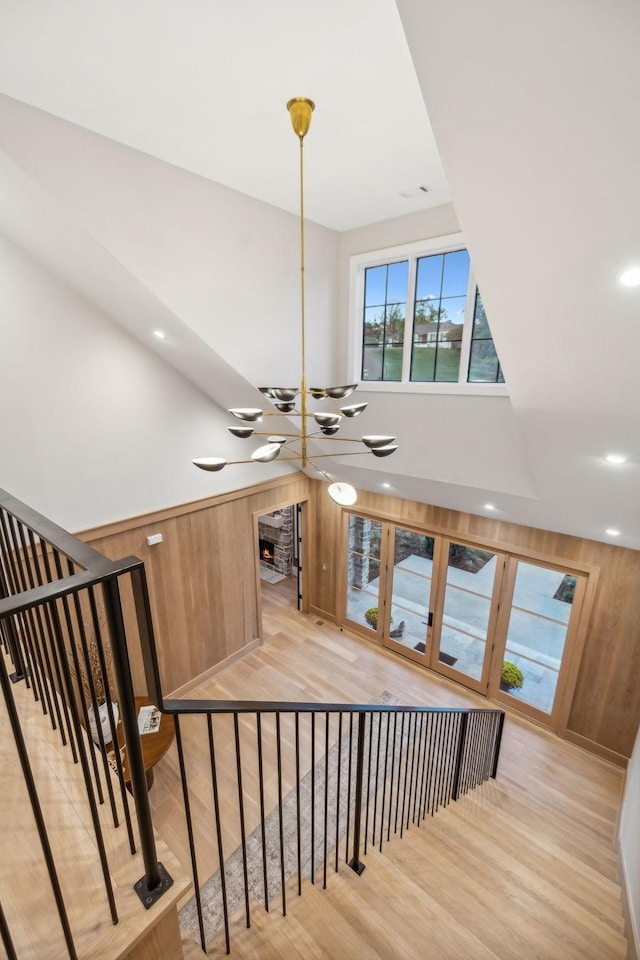 stairway featuring hardwood / wood-style floors, wooden walls, and an inviting chandelier