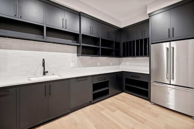 kitchen featuring high quality fridge, decorative backsplash, sink, and light hardwood / wood-style floors