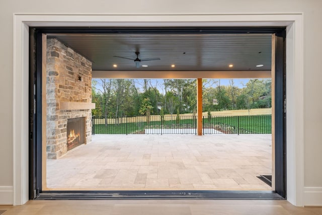 doorway to outside featuring ceiling fan and an outdoor stone fireplace