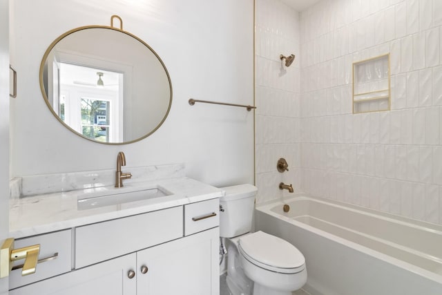 full bathroom featuring tiled shower / bath combo, vanity, and toilet