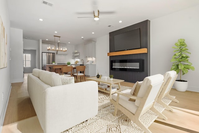 living room featuring a fireplace, light hardwood / wood-style floors, sink, and ceiling fan