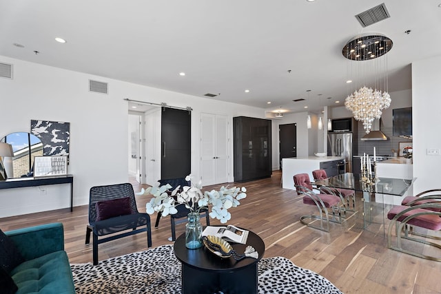 living room featuring a barn door, dark wood-type flooring, and an inviting chandelier