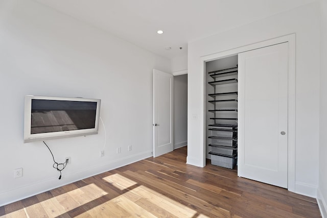 unfurnished bedroom with dark hardwood / wood-style flooring and a closet