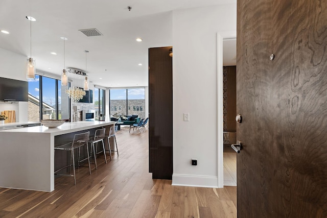 kitchen featuring a breakfast bar, pendant lighting, a wall of windows, hardwood / wood-style floors, and a kitchen island