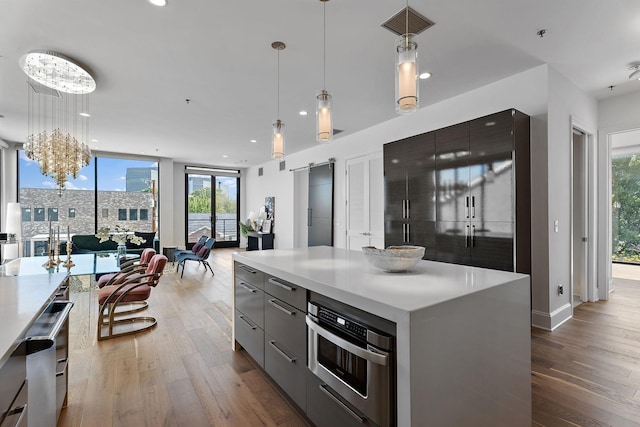 kitchen with pendant lighting, a barn door, a kitchen island, and wood-type flooring