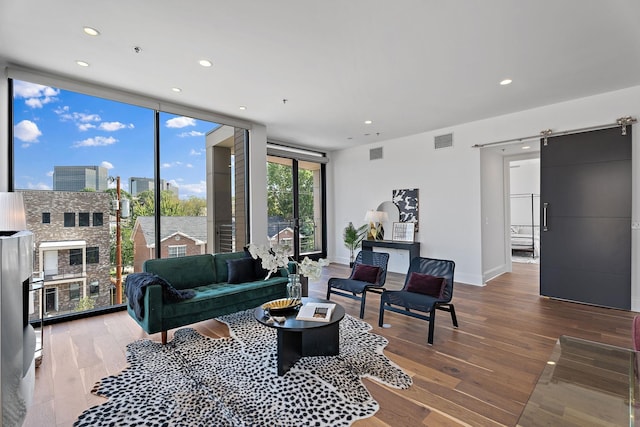 living room featuring a barn door, hardwood / wood-style flooring, and expansive windows