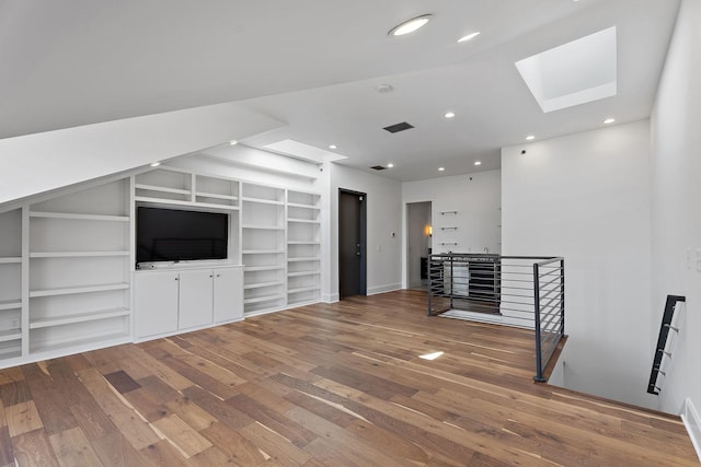 unfurnished living room featuring a skylight, built in features, and hardwood / wood-style flooring