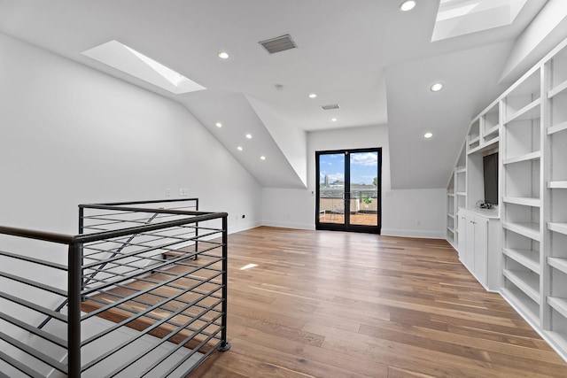 bonus room with hardwood / wood-style floors, built in features, french doors, and vaulted ceiling with skylight