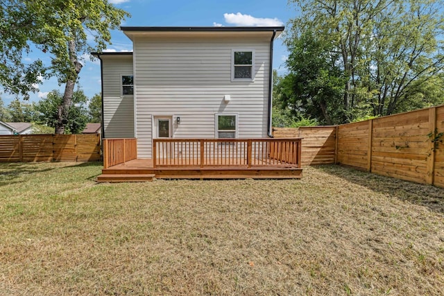 back of property featuring a wooden deck and a lawn