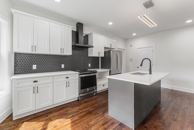 kitchen featuring appliances with stainless steel finishes, white cabinetry, an island with sink, sink, and wall chimney range hood