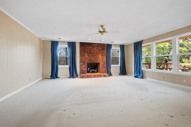 unfurnished living room featuring ceiling fan, a textured ceiling, a fireplace, carpet, and ornamental molding