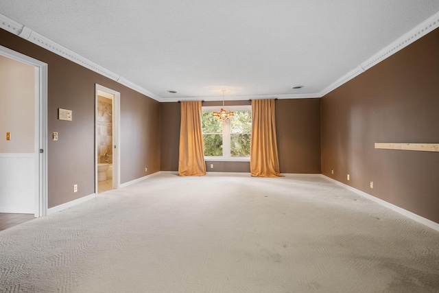 carpeted spare room featuring an inviting chandelier and ornamental molding