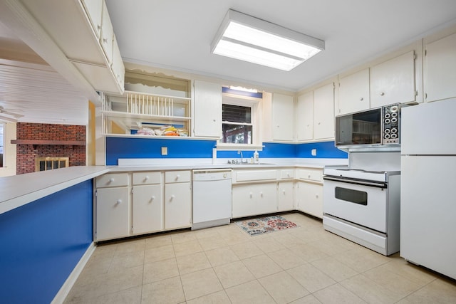 kitchen with a fireplace, white appliances, white cabinets, and sink