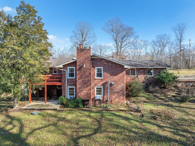 rear view of house with a lawn, a wooden deck, and a patio