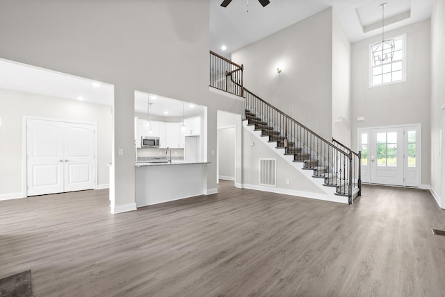 unfurnished living room with ceiling fan, sink, a towering ceiling, and dark hardwood / wood-style flooring