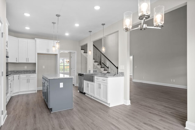 kitchen with dishwasher, sink, white cabinetry, and pendant lighting