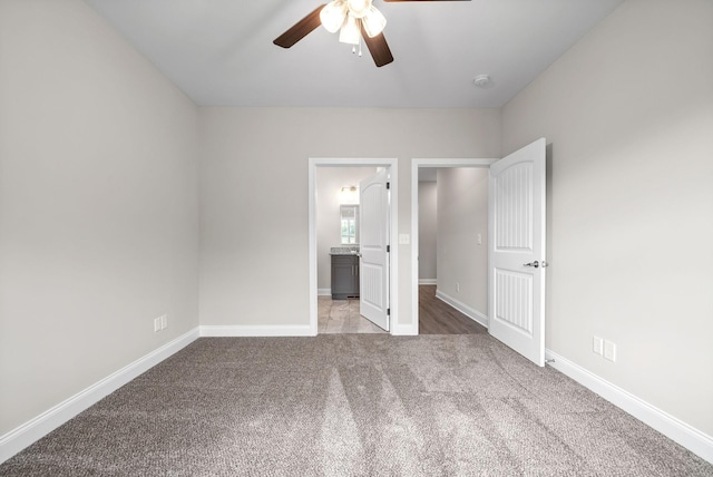 unfurnished bedroom with ceiling fan, a closet, light colored carpet, and ensuite bath