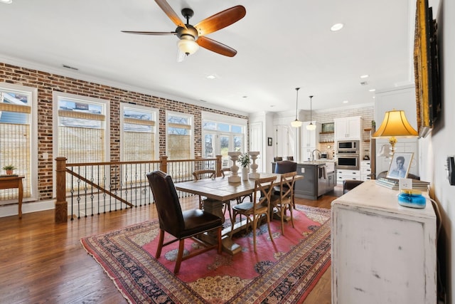 dining area featuring ornamental molding, brick wall, ceiling fan, dark wood-type flooring, and sink