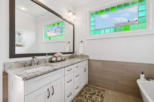 bathroom featuring a washtub, tile patterned flooring, crown molding, vanity, and tile walls