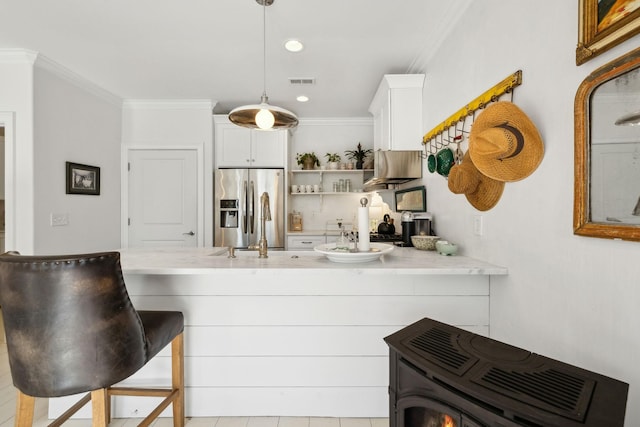 kitchen with a kitchen bar, kitchen peninsula, pendant lighting, white cabinets, and stainless steel fridge with ice dispenser