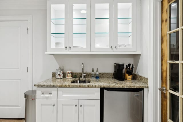 bar with white cabinets, refrigerator, light stone countertops, and sink