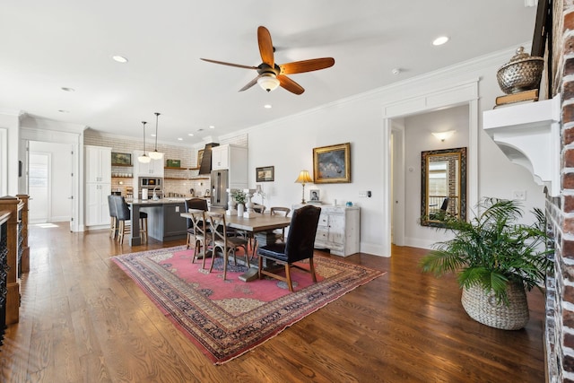 dining space with ornamental molding, a brick fireplace, ceiling fan, and dark wood-type flooring