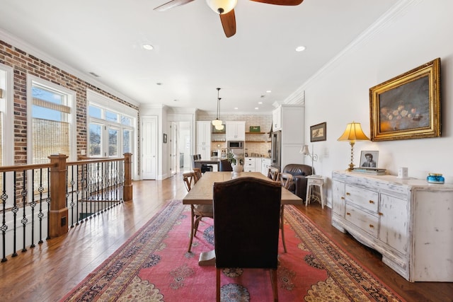 dining area with ceiling fan, crown molding, dark wood-type flooring, and brick wall