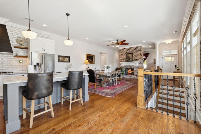 kitchen featuring a kitchen breakfast bar, light stone counters, decorative light fixtures, white cabinets, and appliances with stainless steel finishes