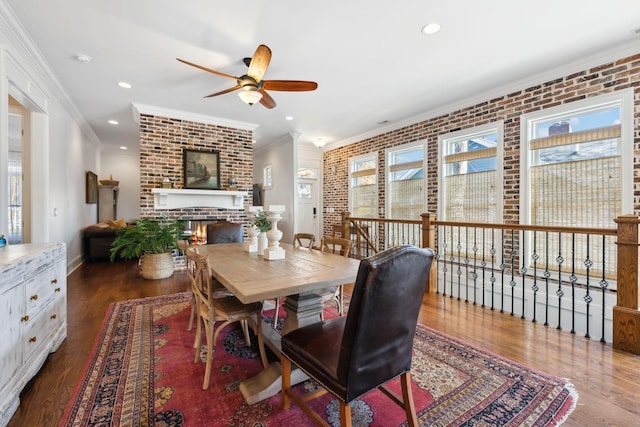 dining space featuring dark hardwood / wood-style flooring, ornamental molding, a fireplace, and brick wall