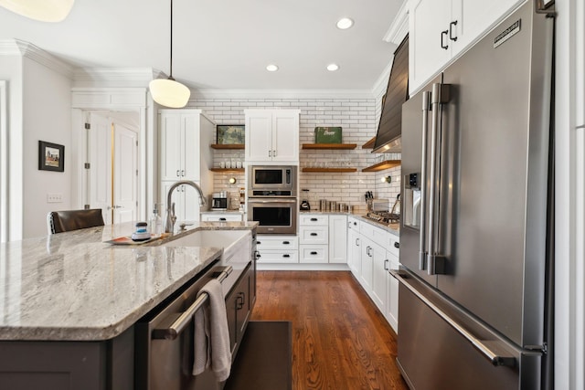 kitchen with appliances with stainless steel finishes, tasteful backsplash, light stone counters, decorative light fixtures, and white cabinetry