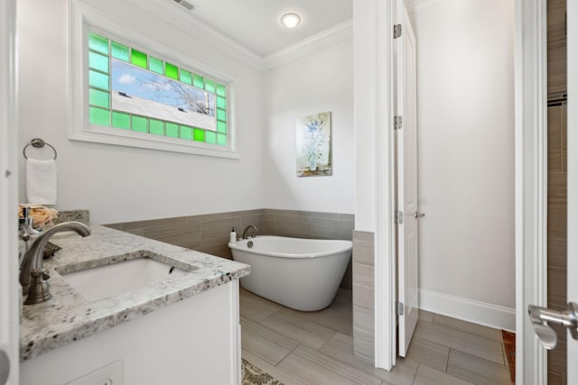 bathroom with vanity, crown molding, a tub, and tile walls