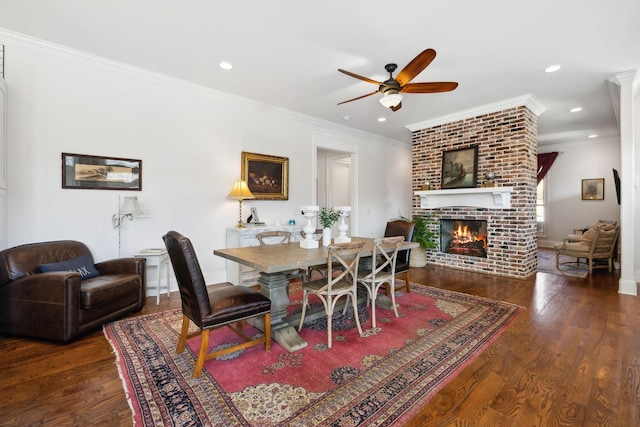 dining room featuring ceiling fan, a fireplace, ornamental molding, and dark wood-type flooring