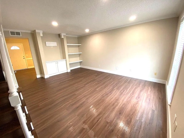 unfurnished living room featuring built in shelves, a textured ceiling, and dark wood-type flooring